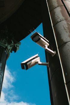 Low angle view of security cameras on a building against a blue sky.
